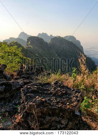 View from mountain mount zwegabin in valley below during sunrise with sun rays beams shining through the fog and mist in the valley