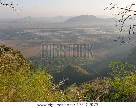 View from mountain mount zwegabin in valley below during sunrise with sun rays beams shining through the fog and mist in the valley