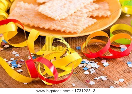 Carnival pastry with confetti on wooden table.