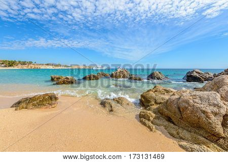 Fantastic sky, ocean and rocks. A sequence of stages of waves on the ocean sand. Playa El Chileno Beach, Cabo San Lucas, Mexico.