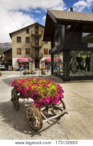 Livigno, Italy - August 1: Wain With Flowers In Front Of Fashion Shops On Streets Of Duty-free Area