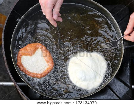 Hands Of Cook Frying Two Large Pancakes In A Pan Of Hot Oil