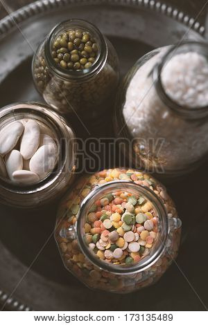 Beans, lentils, rice in a glass jar on a plate vertical
