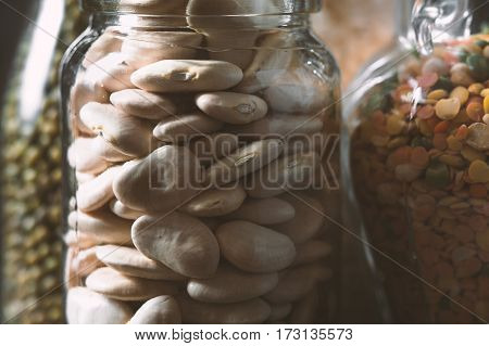 Large white beans in a glass jar is a side view horizontal