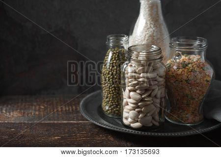 Lentils, white beans, rice in glass bottles copy space horizontal
