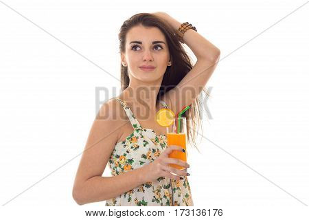 young beauty girl in sarafan with floral pattern drinks organe fresh cocktail and looking aside isolated on white