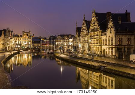 GHENT BELGIUM - 18TH FEB 2016: A view of beautiful old buildings along Korenlei Graslei and the River Leie in Ghent Old Town at night. Reflections can be seen in the water.