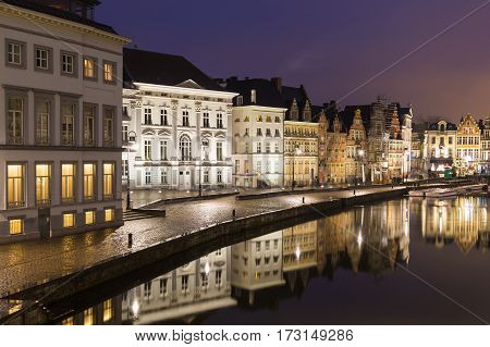 GHENT BELGIUM - 18TH FEB 2016: A view of beautiful old buildings along Korenlei and the River Leie in Ghent Old Town at night. Reflections can be seen in the water.