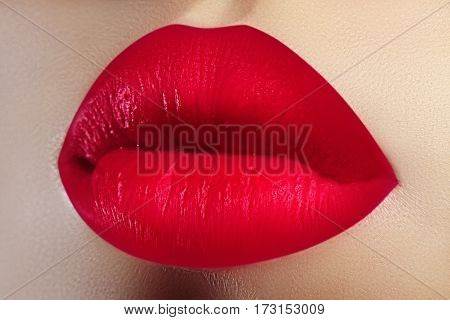 Cosmetics makeup and trends. Bright lip gloss and lipstick on lips. Closeup of beautiful female mouth with red lip makeup. Beautiful part of female face. Perfect clean skin. Valentine sweet kiss