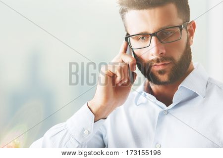 Close up portrait of handsome caucasian guy in specs talking on the phone. Communication concept