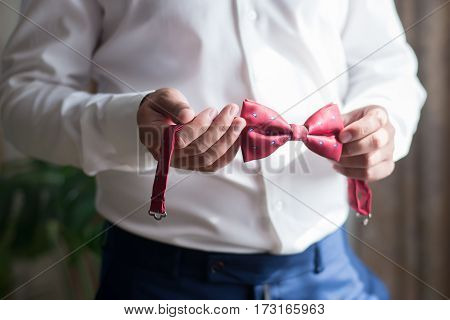 Man in white shirt holds a red bow tie