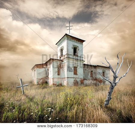 Abandoned church near the cemetery in a field