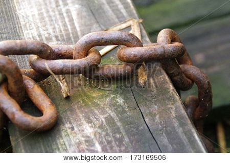 Thick rusty chain on a background of the old board