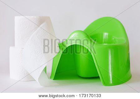 White toilet paper beside child's green potty on white background.