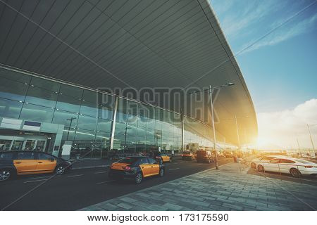 Cabstand in front of modern airport doors in Barcelona cabrank with a lot of taxies near windowed facade of contemporary Airport terminal in Spain with road long ceiling and parking lot