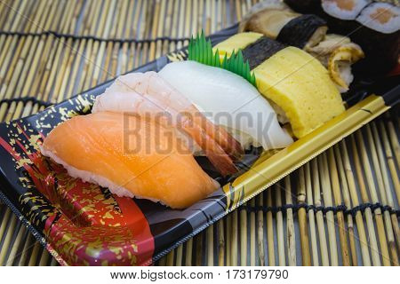 Sushi set sashimi and rolls served on traditional plate and mat