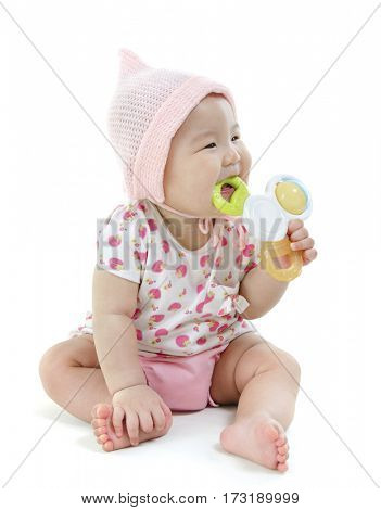 Portrait of full length beautiful Asian baby girl in pink clothes biting teether toy, isolated on white background.
