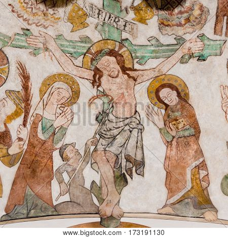 The crucifixion of Jesus on Good Friday. His mother Mary and St. John standing at the cross with the heading INRI. Gothic fresco in Skibby church Denmark - February 21 2017