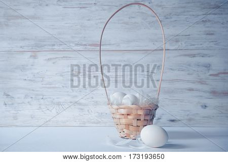 easter eggs in basket on white wooden background