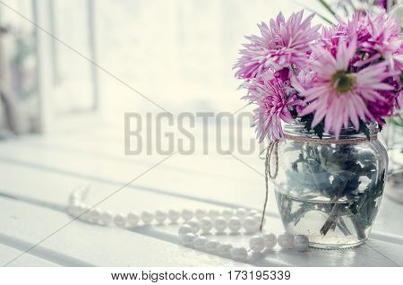 Beautiful pink and purple bouquet in glass vase over window. Light home decoration with flowers asters. Provence style interior retro living room. Vintage holiday floral concept. Copy space.