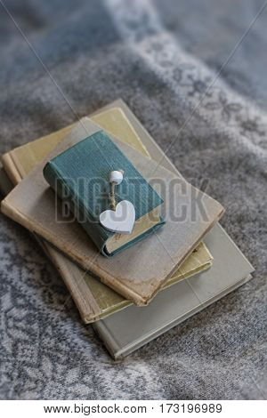 old book and a wooden heart lies on a sweater. cold tone. soft focus background