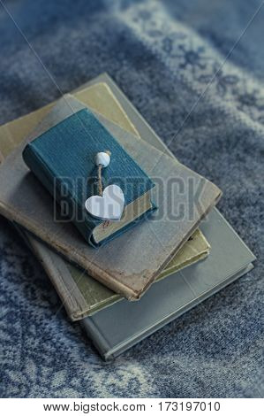 old book and a wooden heart lies on a sweater. cold tone. soft focus background