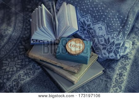 old book and a wooden heart lies on a sweater. warm tone. background. soft focus