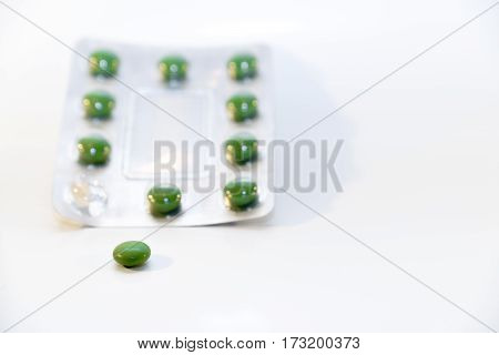 Green pills in blister package isolated on white
