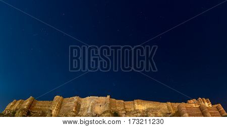 Details of Jodhpur fort at night. The majestic fort perched on top with clear blue starry sky above. Orion constellation and the Pleiades. Travel destination in Rajasthan India.