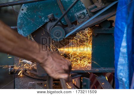Metal grinding on steel pipe with flash of sparks close up