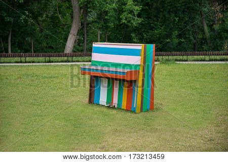 Colorful old piano standing on a meadow in the Park