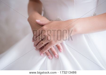 Young bride in wedding dress gently holding her hands with fingers with a ring
