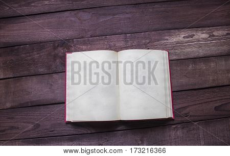 Open red book on wooden desk with soace for text