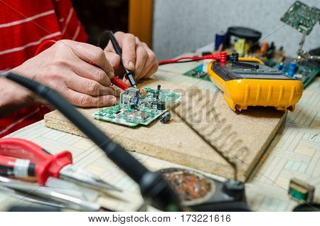man hands closeup repair electronic device using Multimetr