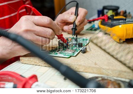 man hands closeup repair electronic device using Multimetr