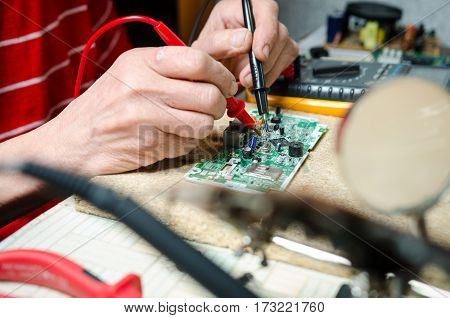 man hands closeup repair electronic device using Multimetr