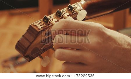 Guitarist's hands tuning the acoustic guitar close-up