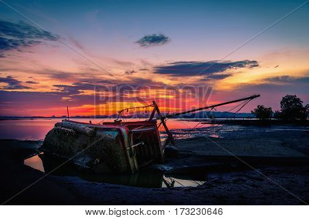 The old fishing boat capsized on sea at sunset in Phuket Thailand.