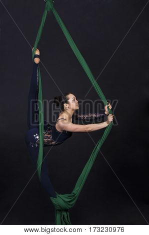 Girl's aerial acrobatics in the paintings - dark background. Studio photography of circus performers