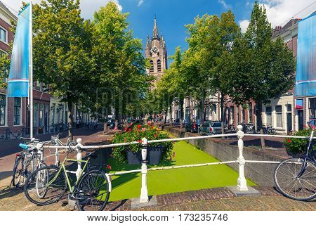 The picturesque Oude Delft canal and leaning tower of Gothic Protestant Oude Kerk church on a sunny day in Delft, South Holland, Netherlands.