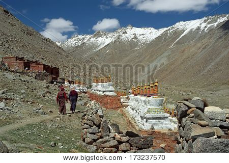 Two Tibetan pilgrim lady go to the monastery Driraphuk Gompa along 108 Buddhist stupas on the slope of Sacred Mount Kailash in Western Tibet.