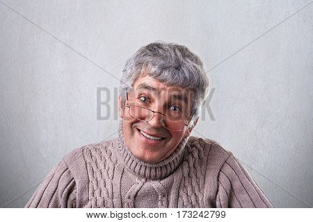 A positive cheerful kind mature man wearing glasses looking kindly into camera having gentle smile. Smiling senior man while standing over white background. Emotions and feelings concept