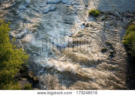 Top view of the turbulent fast mountain river on a sunny summer day