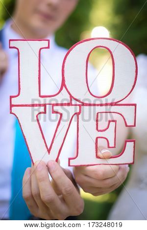 word love on wooden red and white plate in the hands of the bride and groom