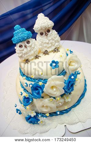 three tiered blue and white wedding cake with confectionery roses and funny figures