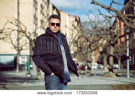 Handsome happy smiling man. Outdoor winter male portrait. Attractive confident middle-aged man in sunglasses walking in city.