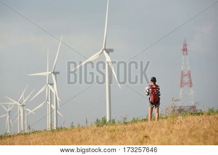 Hipter woman backpacker a lone travel and wind turbines on background