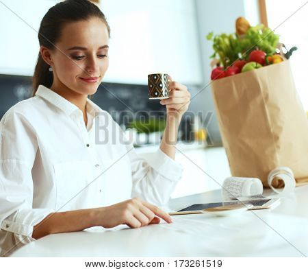 Young woman planning expenses and paying bills on her kitchen