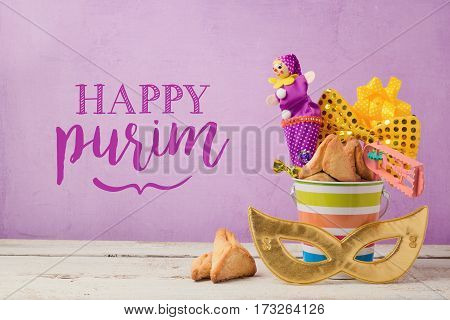 Purim holiday greeting card with carnival mask and gifts over purple background