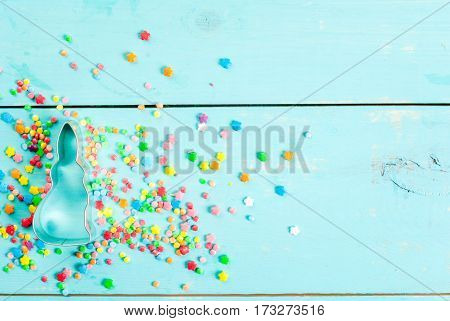 Easter background with cookie cutter in shape of symbol of Easter - Bunny and sugar sprinkles for cookies and cakes top view copy space